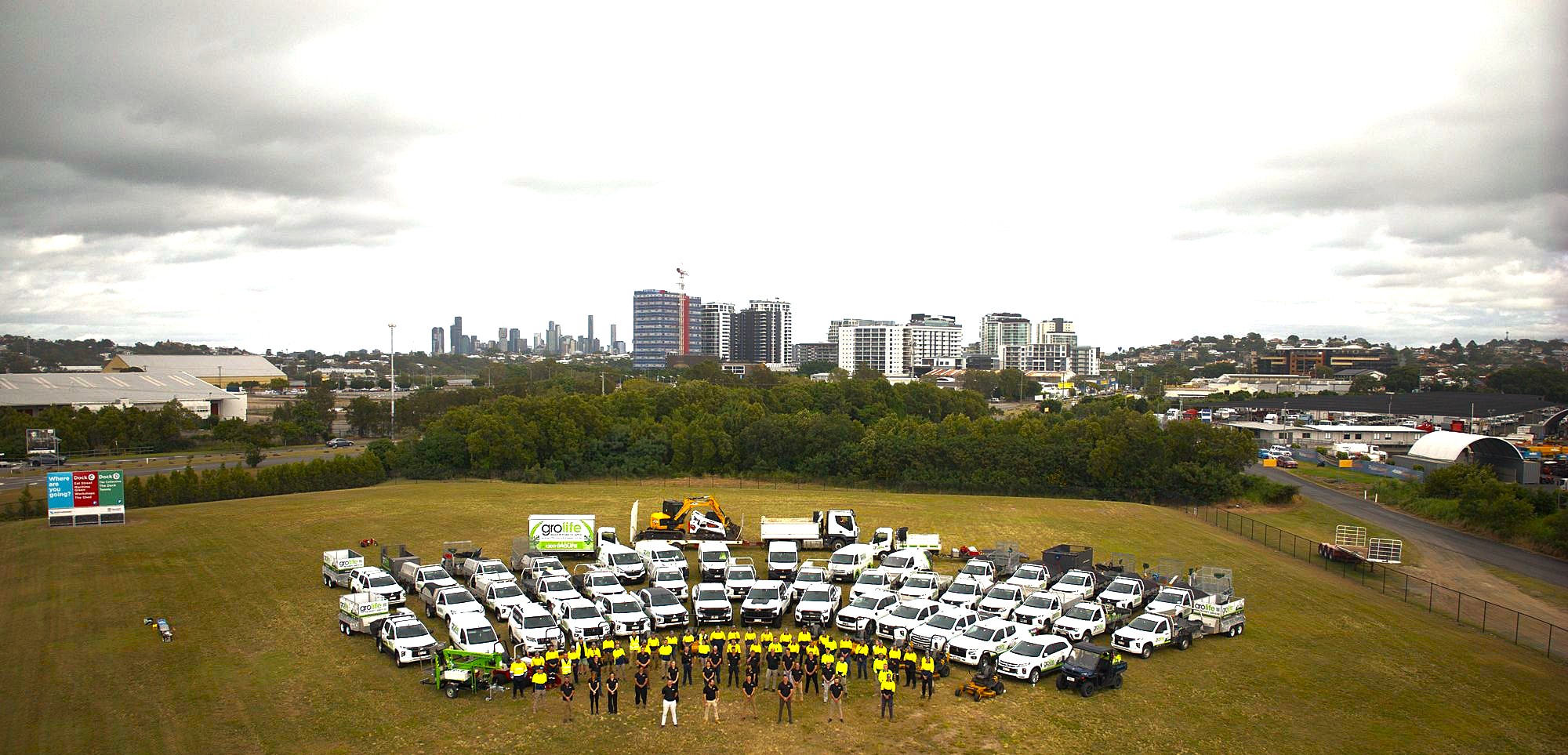 The full Grolife team and fleet — aerial shot of the vehicles arranged in formation with Brisbane skyline in the background